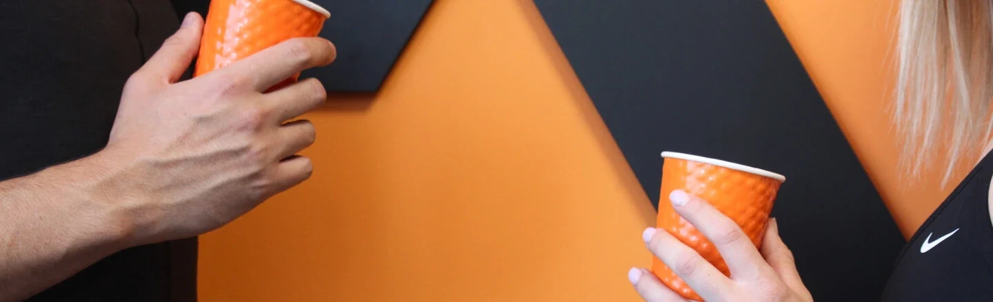 לחיים! צולם בכניסה לסטודיו LK באר יעקב לירון קרני וגל ויסמן (מתאמן ובעל הסטודיו) מחזיקים כוסות כתומות על רקע הלוגו בסטודיו LK